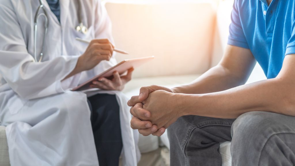 A doctor and patient have a discussion in an exam room.