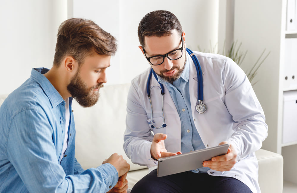 A Physician Reviews Test Results With A Patient In An Office