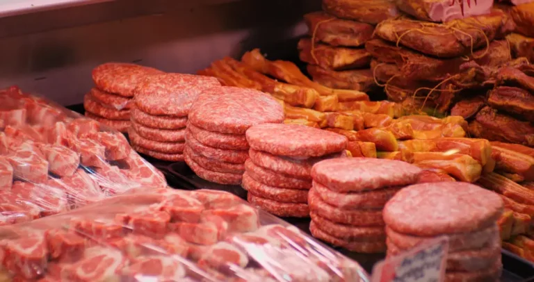 A variety of red and processed meats sit in a butcher’s case.