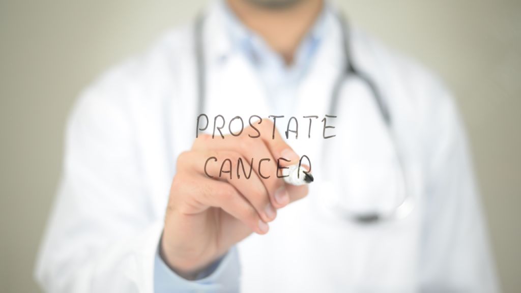A physician writes the words “Prostate Cancer” on a transparent panel.