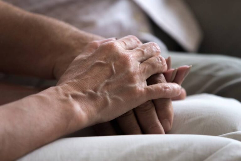 A close-up view of a senior couple holding hands.