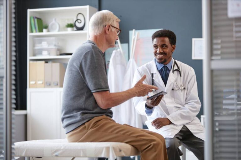 A physician consults with a patient in an exam room.