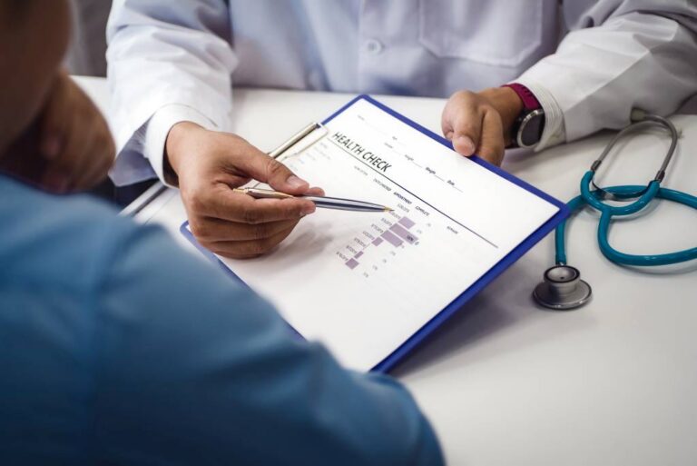 A physician points out exam results to a patient on a piece of paper.